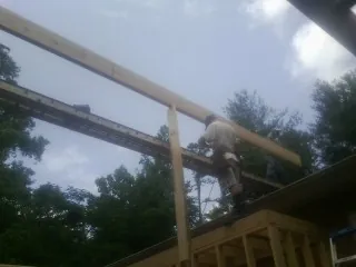 Carpenter setting a ridge beam over a new addition frame — Ice Dam Removal by Roofing Brothers in Okmulgee