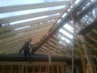 Rafters going up over a new addition with a worker on the wall in Okmulgee
