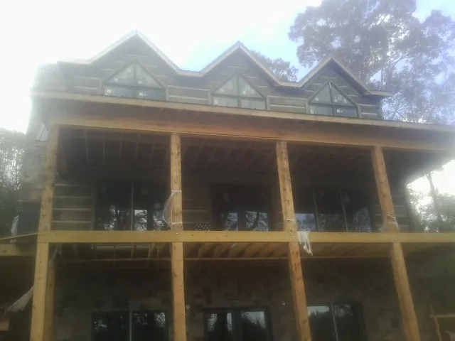 Dormers and porch framing on a large log home under construction — Roof Coating work by our crew in Okmulgee