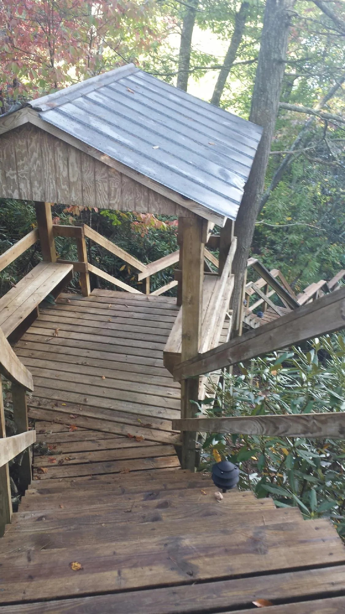 Metal roofed shelter over wooden steps on a wooded walkway — Skylight Repair & Installation work by our crew in Okmulgee